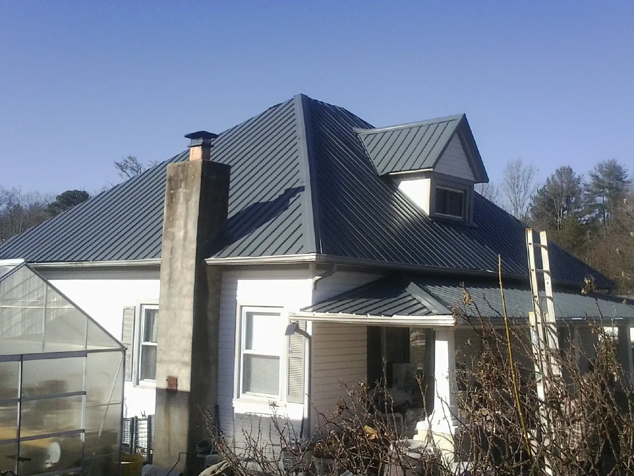 Dark blue standing seam metal roof on a white farmhouse with dormer — Slate & Tile Roof Repair by Roofing Brothers in Travelers Rest