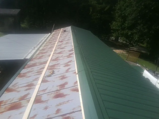 Old rusted panels beside newly installed green metal roofing — Wind Damage Roof Repair by Roofing Brothers in Travelers Rest