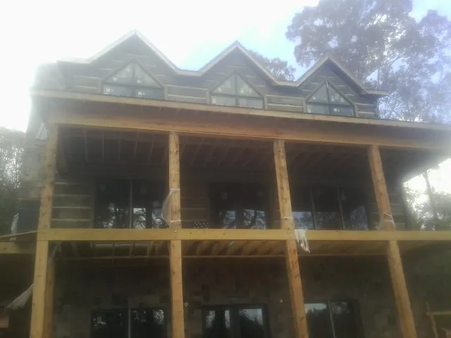 Dormers and porch framing on a large log home under construction — Roof Coating work by our crew in Travelers Rest