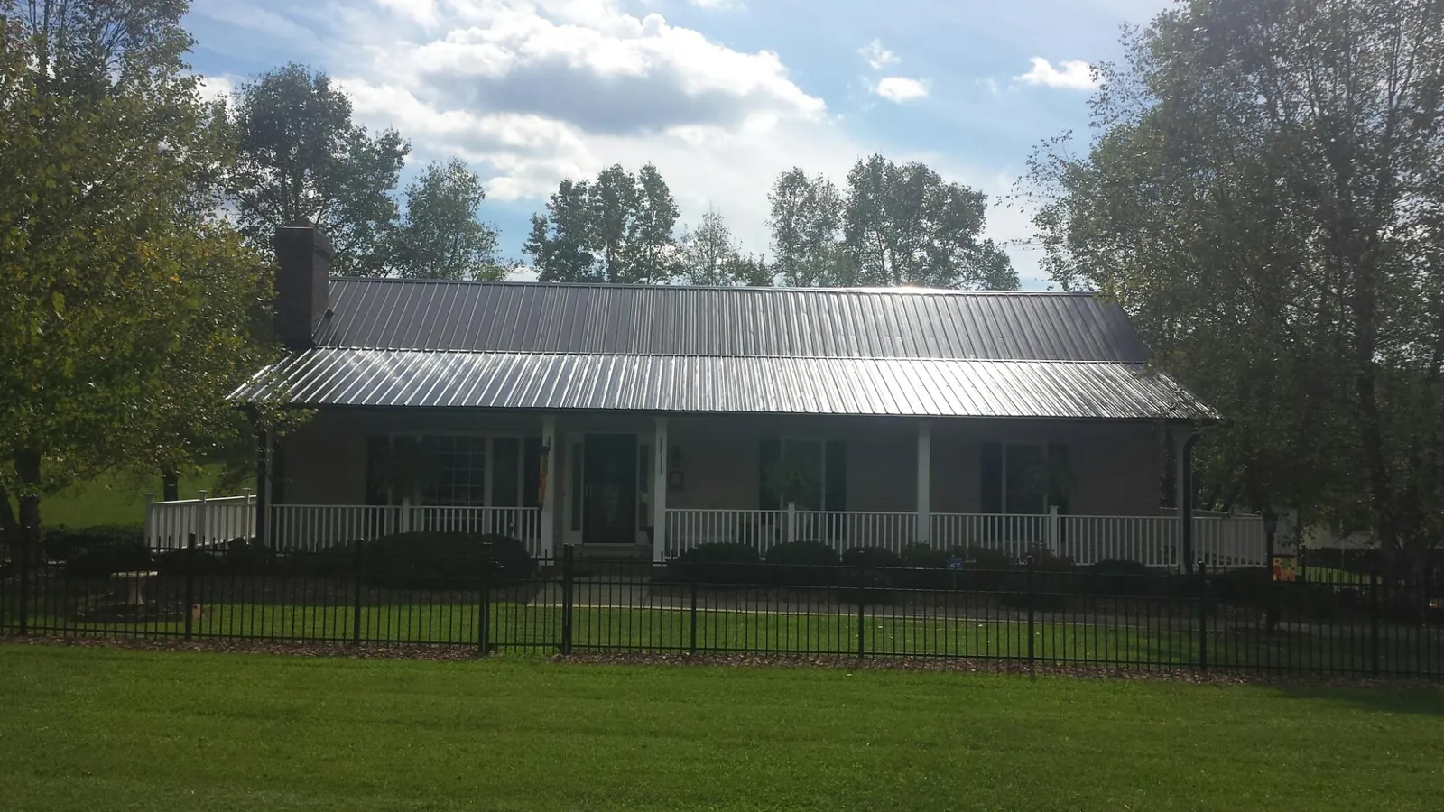 Gray metal roof on a brick ranch with a full width front porch — Gutter Guard Installation work by our crew in Travelers Rest