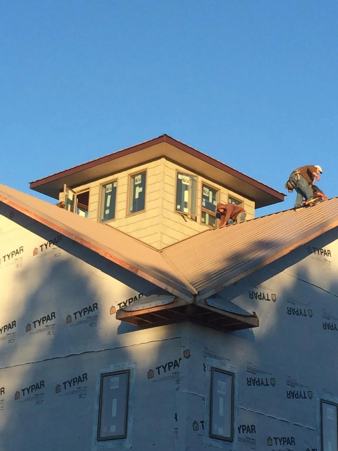 Roofers working around a rooftop cupola on a new metal roof at sunset — Roof Waterproofing in Travelers Rest by Roofing Brothers